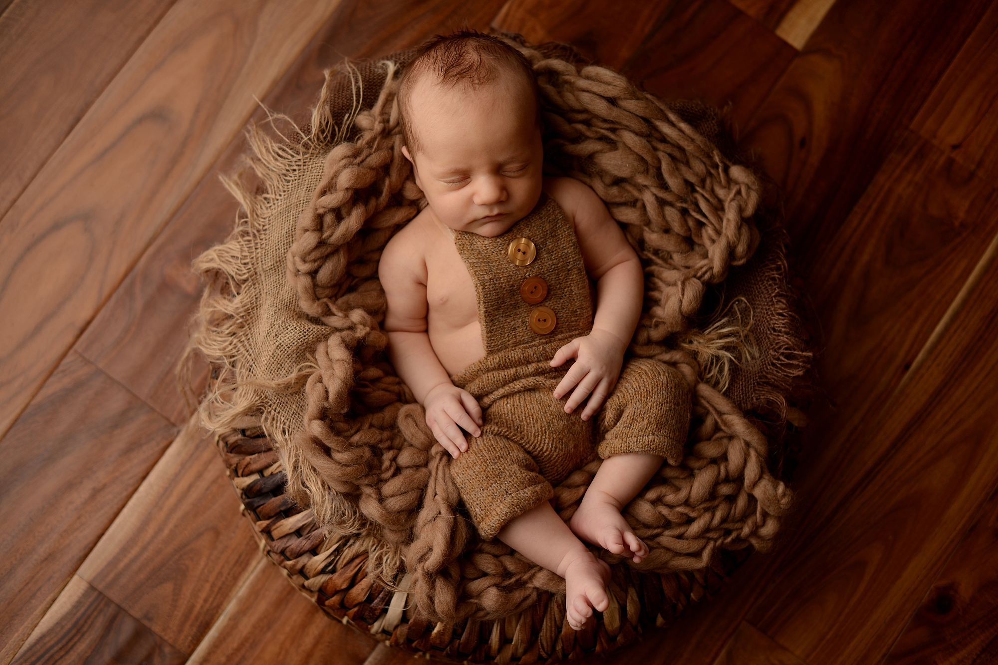 Newborn Photos of a boy sleeping in a basket at a queens newborn photography studio