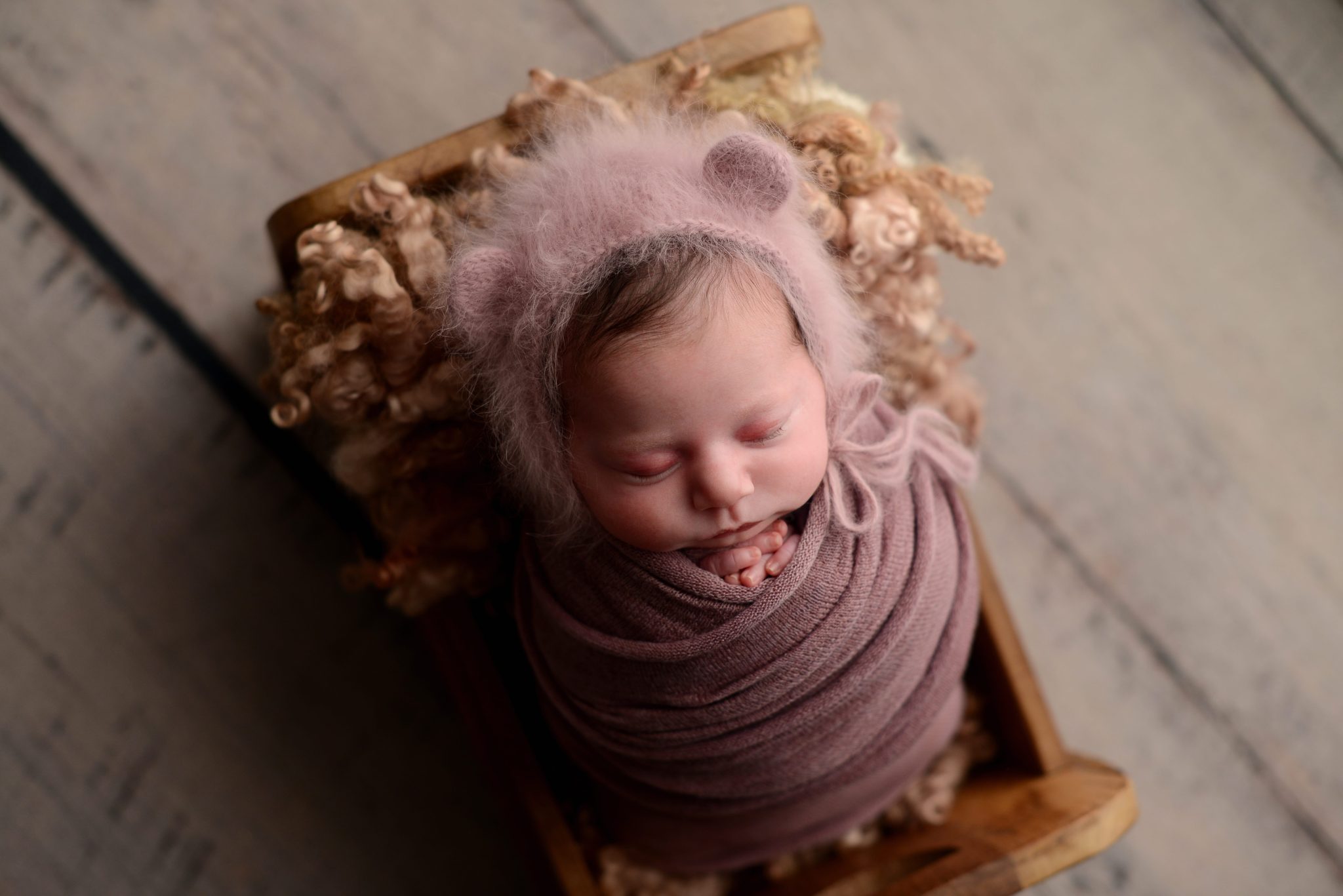 Newborn baby girl wrapped in purple at Queens Portrait Studio