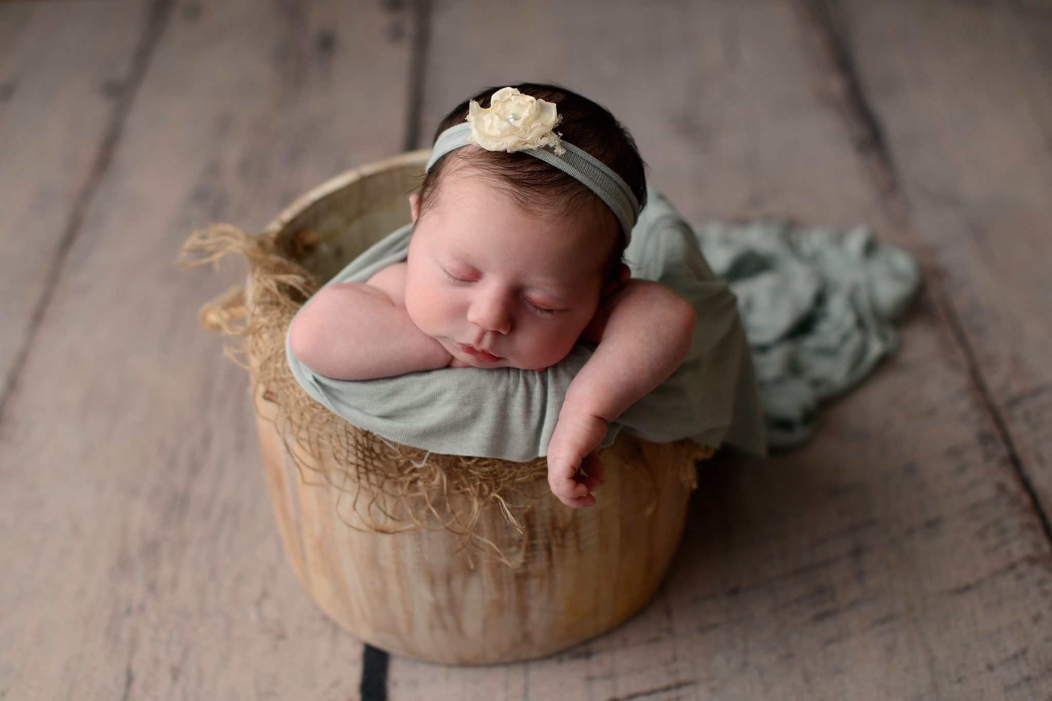 Newborn baby girl asleep in a basket at Queens Portrait Studio