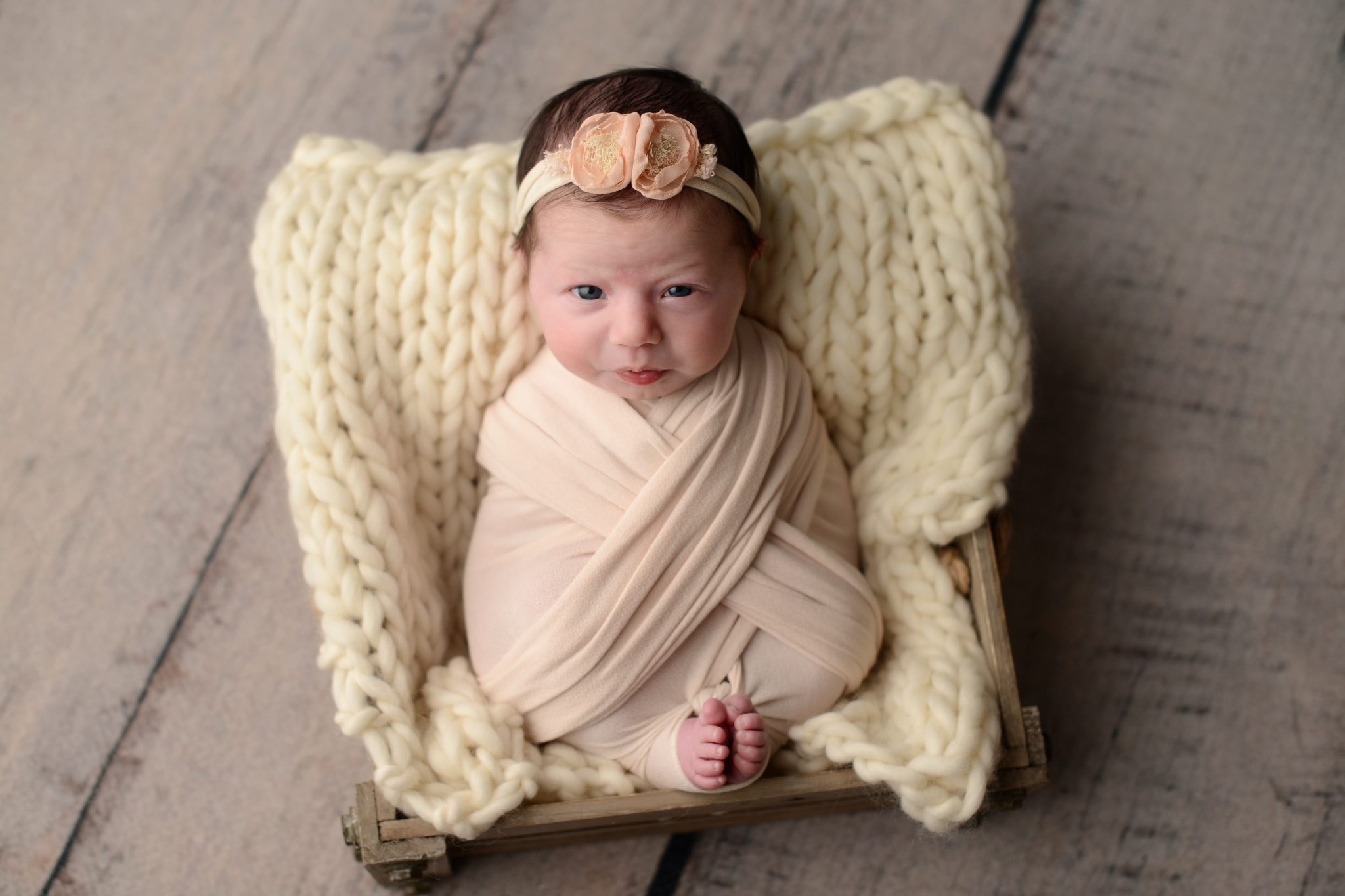 Newborn baby girl photo wrapped in cream at Queens Portrait Studio