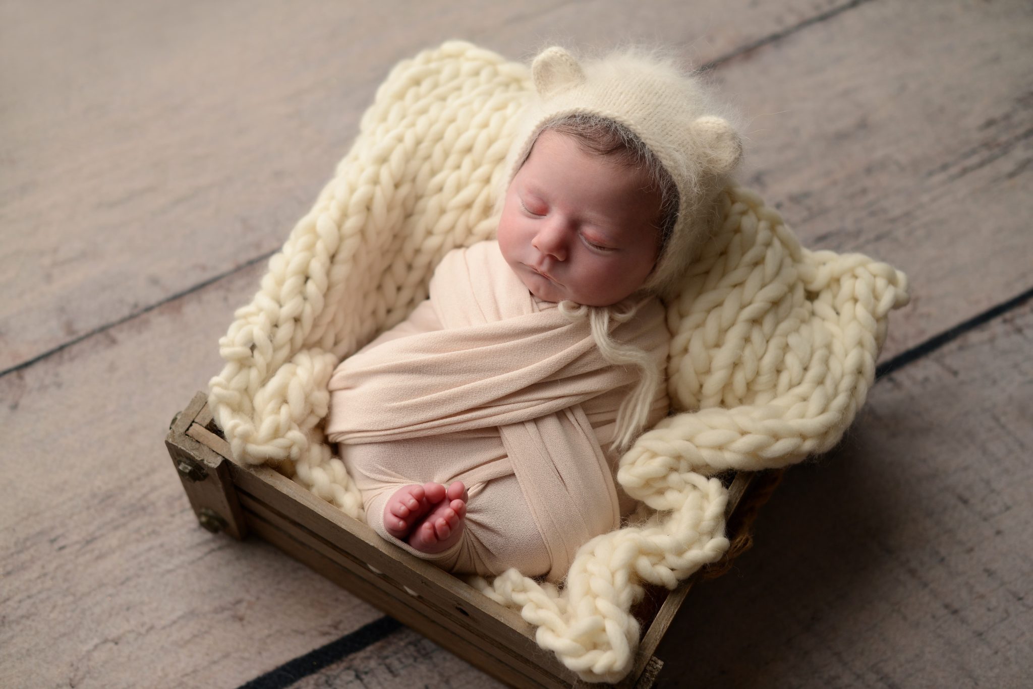Newborn baby girl asleep in a basket in Queens Portrait Studio