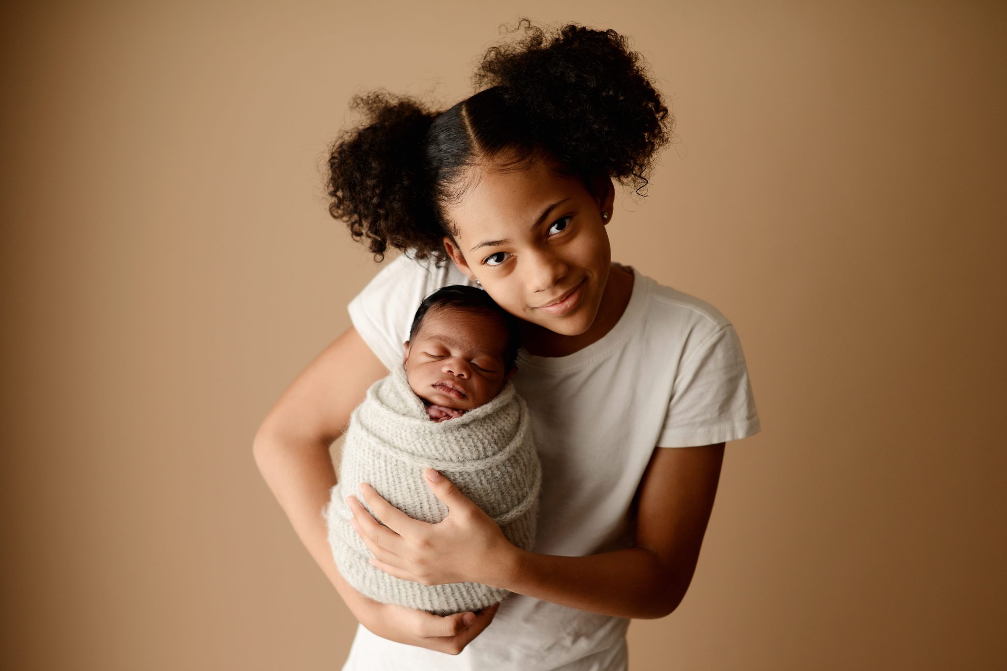 Tips for Great Newborn Photos: teenage sister holding newborn baby brother