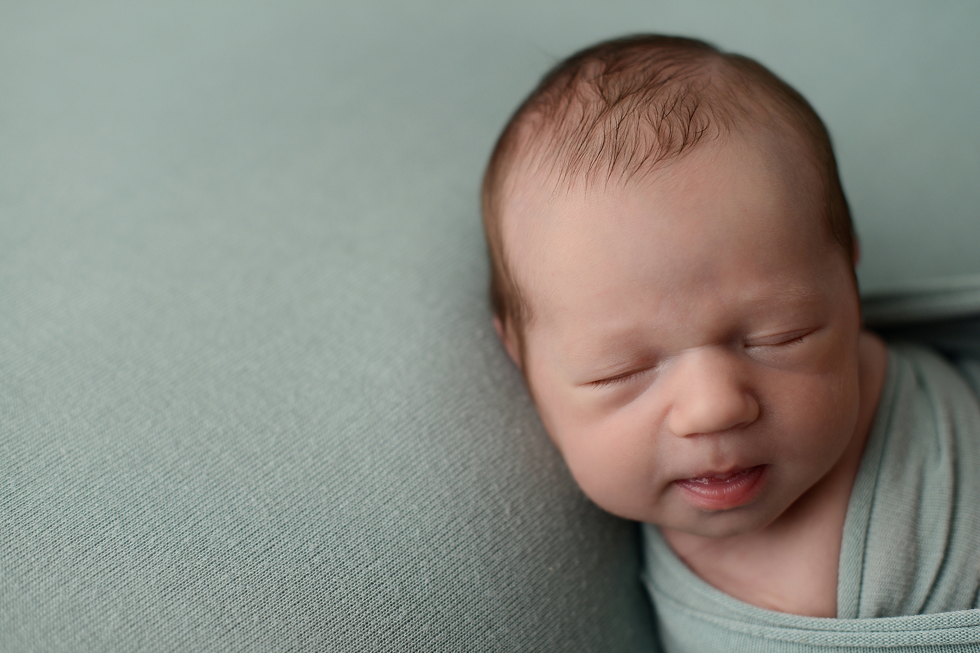 Newborn baby boy on green backdrop in Queens Photography Studio
