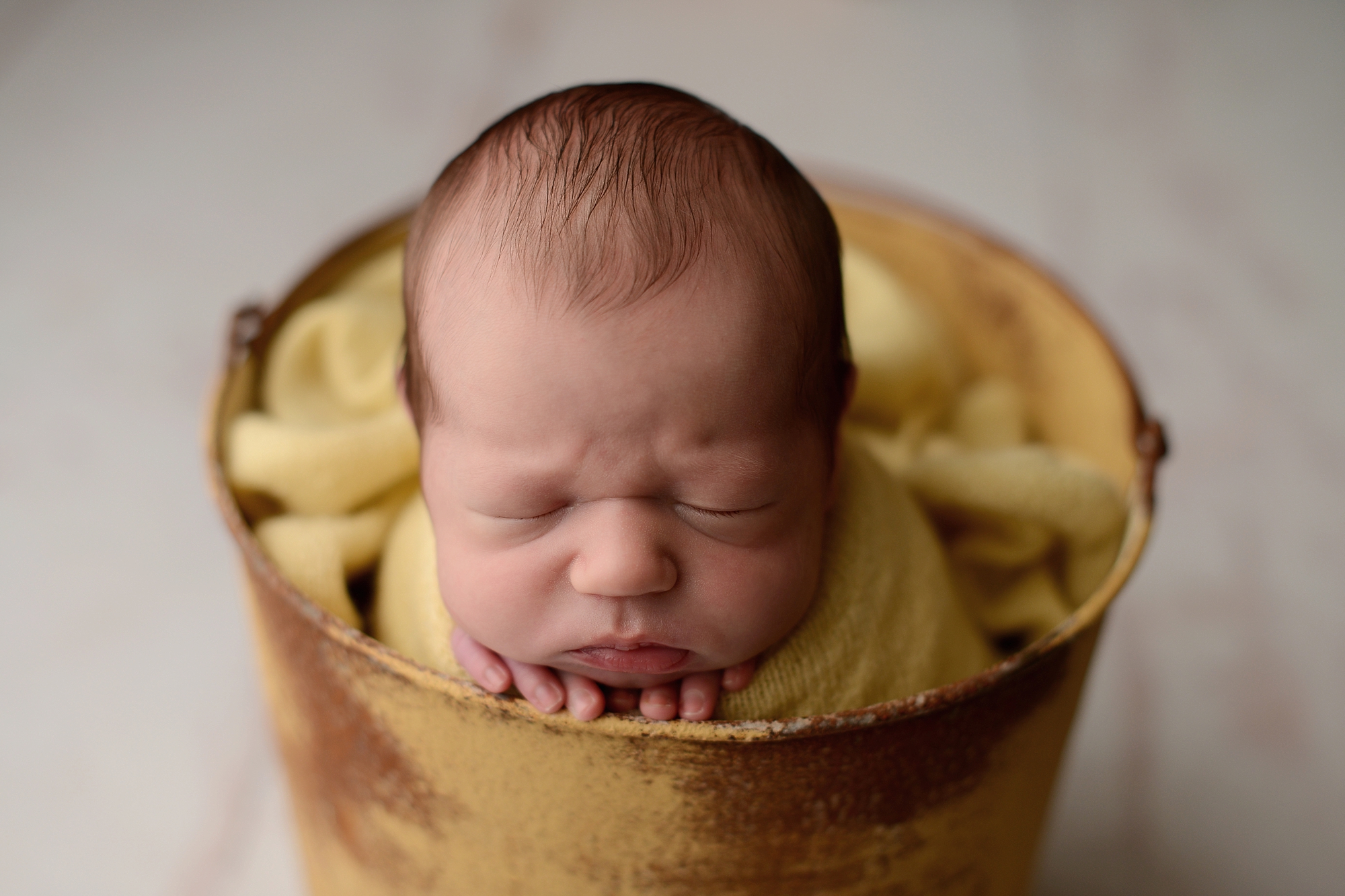 Newborn baby boy in yellow bucket in Queens Photography Studio
