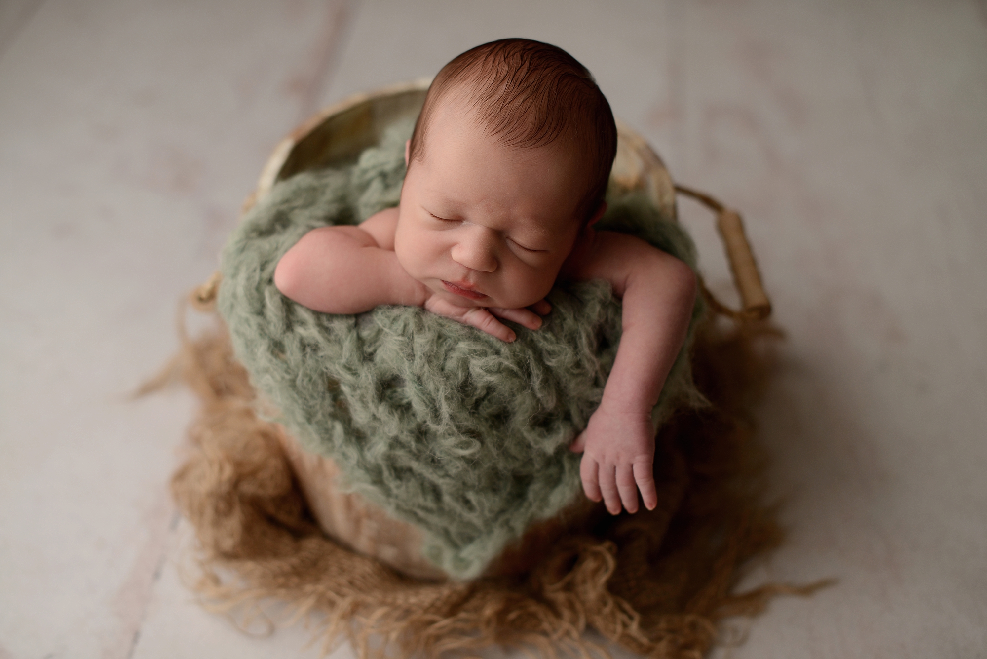 Newborn baby boy in green bucket in Queens Photography Studio