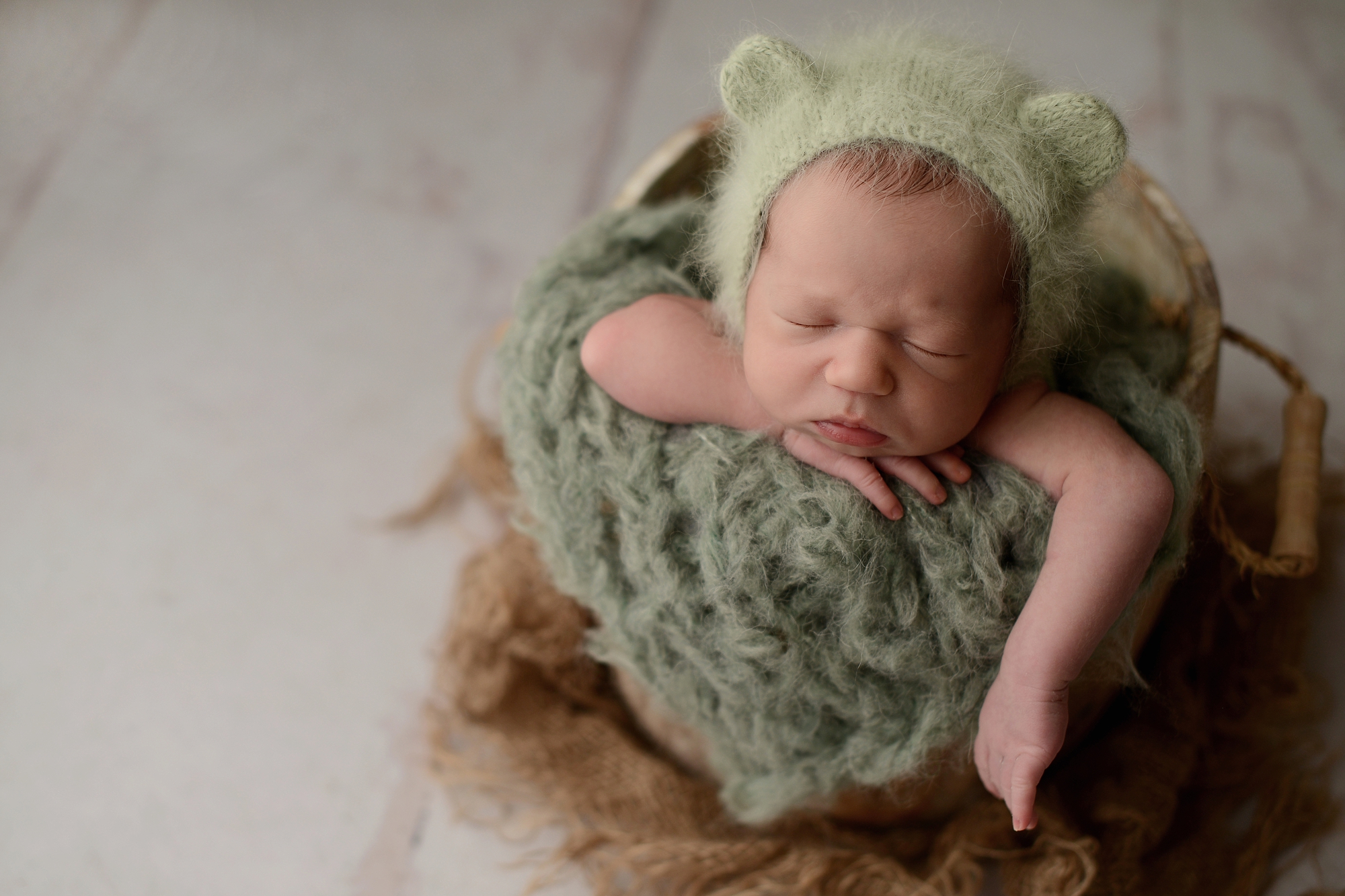 Newborn baby boy in green bucket in Queens Photography Studio