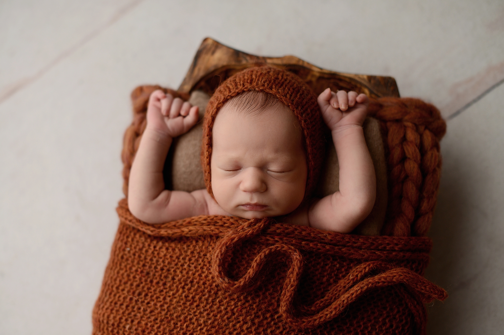 Newborn baby boy in burnt orange box in Queens Photography Studio